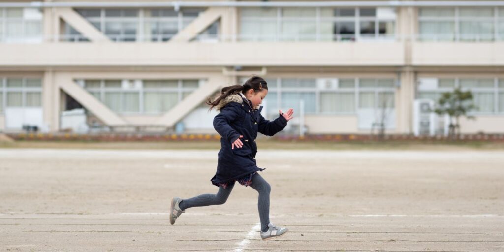 小学校の校庭を走る女の子の画像。