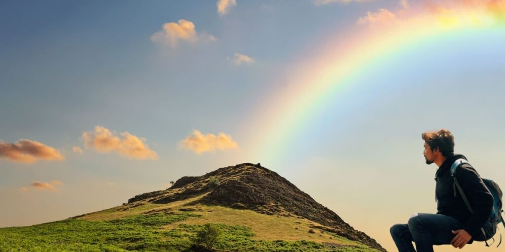 A man led to a good future

虹を見つめ山に登る男の画像。