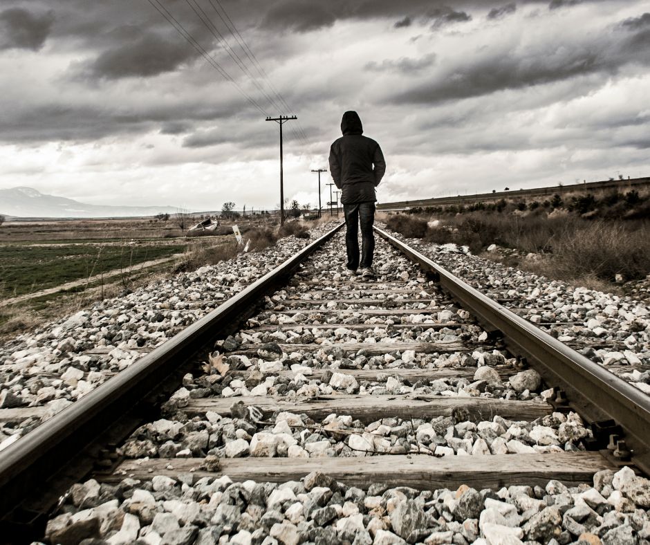 A man walking on the railroad tracks and moving away