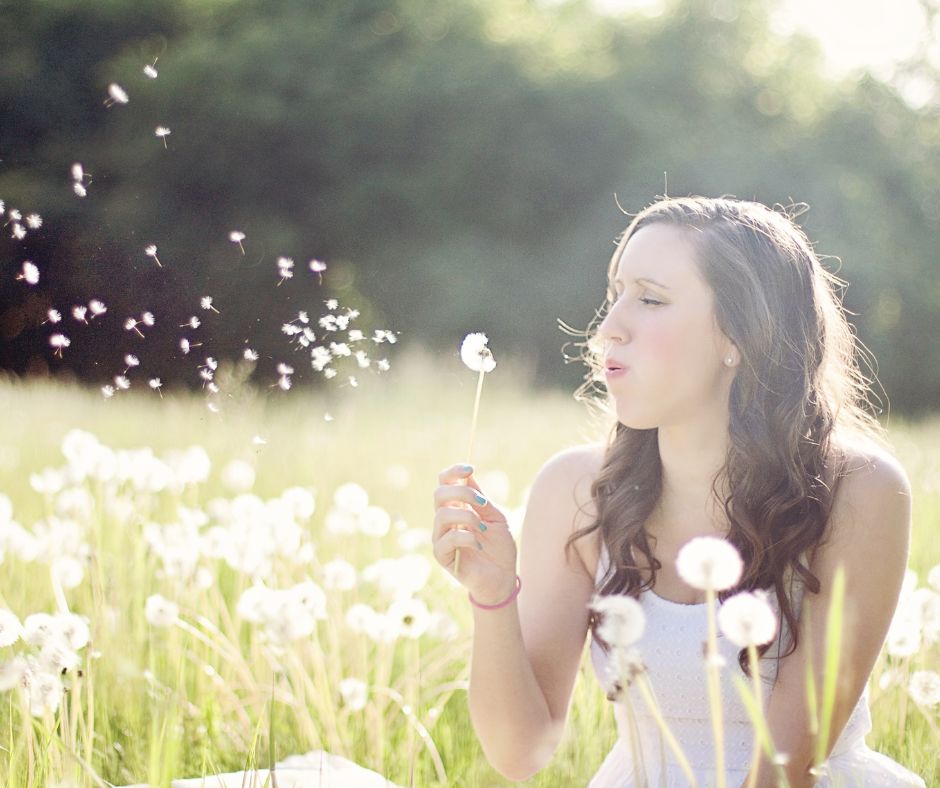 A woman blowing dandelion seeds